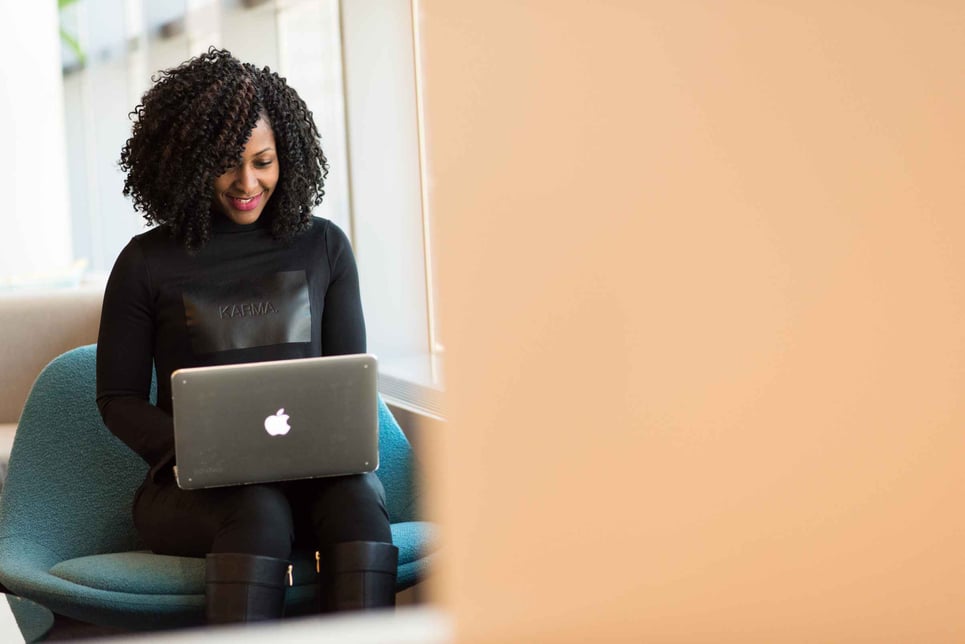 A woman sitting in front of a laptop creating an email signature for Apple Mail