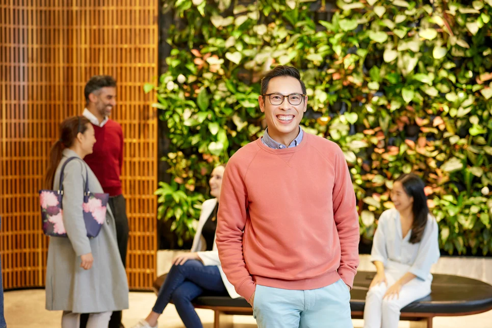 A man in a red sweater is standing in front of a group of people.