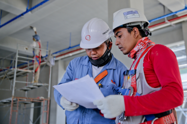 Two men on a work site consulting a document