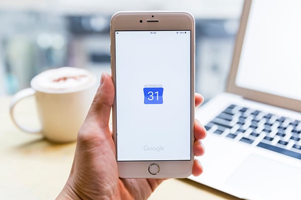 Hand hält Handy mit Google-Kalender App auf Screen