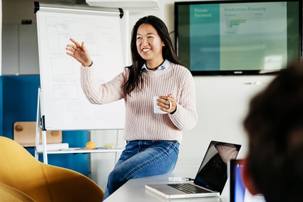Frau hält Vortrag mit Hilfe PowerPoint-Folienmaster im Hintergrund