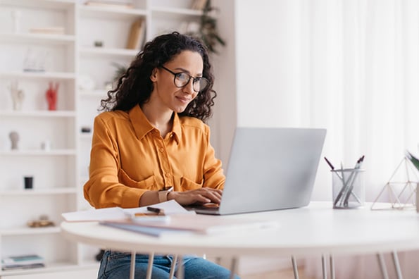 Frau fügt Video in PowerPoint Präsentation am Laptop ein