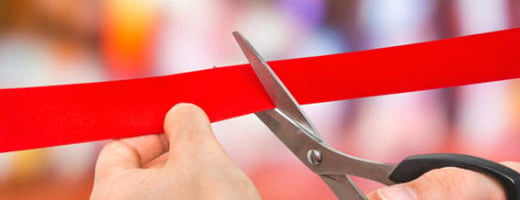 a business owner cuts a red ribbon after bringing their product to market