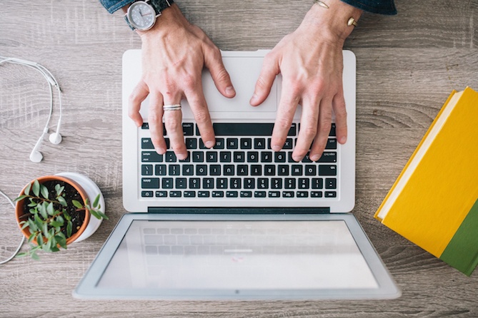 Hands typing on laptop keys.