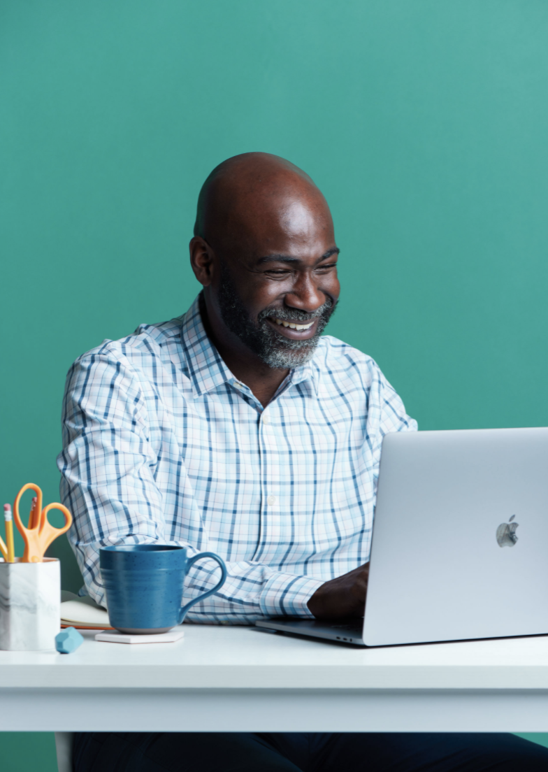 Un homme souriant assis face à un ordinateur portable