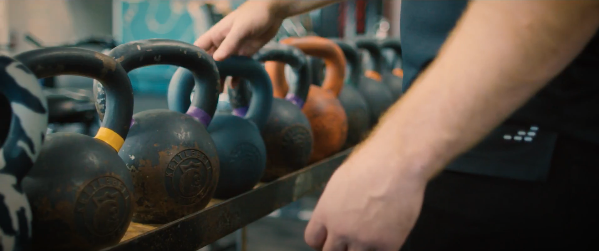 person reaching for kettlebell in gym