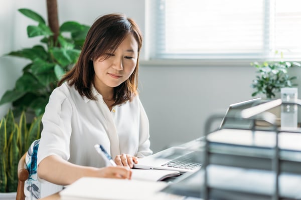 woman at her desk taking notes