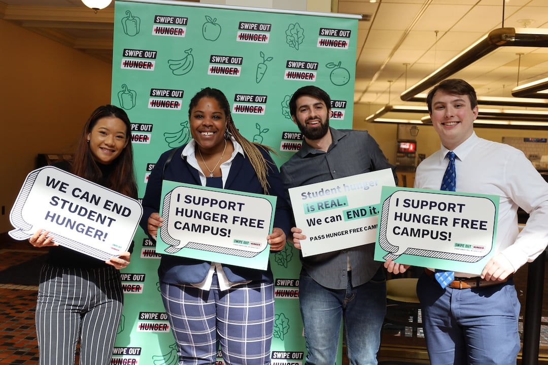 A group of college students holding signs that say 