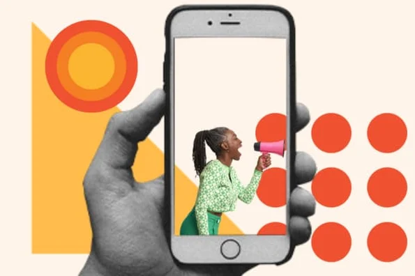 A person uses an iPhone to film a woman with a megaphone.