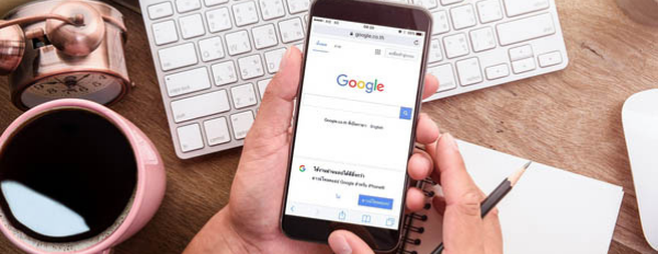 Person holds phone in hand that shows Google homepage