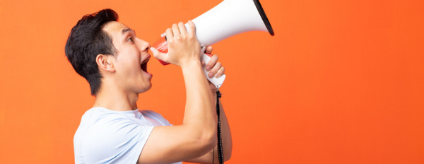 Man stands in front of orange background and yells into a megaphone