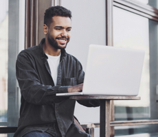 man using a laptop and smiling