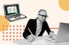 A man with glasses looks at his laptop and scribbles notes on pen and paper.