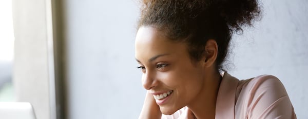 Woman sits at desk smiling at computer screen as she assesses how to integrate her data