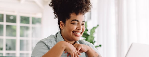 Marketer sits smiling in front of computer while researching facebook ad software to create future campaigns