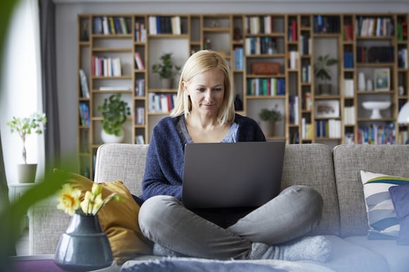 imagem de pessoa sentada com um laptop no colo escrevendo um post de blog 