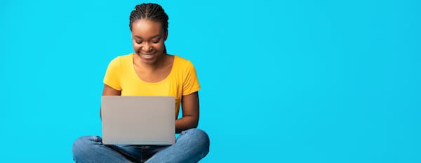 Marketer sits on floor with crossed legs and a computer on their lap to execute a LinkedIn marketing strategy