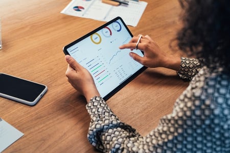 mulher analisa métricas de marketing em um tablet, utilizando dados do Google Search Essentials 