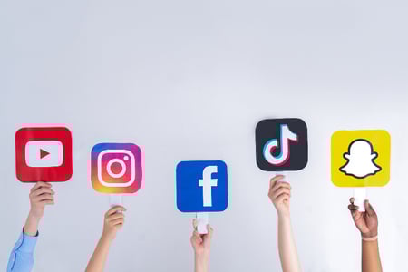 mãos seguram placas com logos de diferentes plataformas de redes sociais 