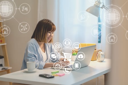 mulher confere os benefícios do varejo omnichannel em seu notebook - ícones representando o conceito multicanal foram adicionados à fotografia original