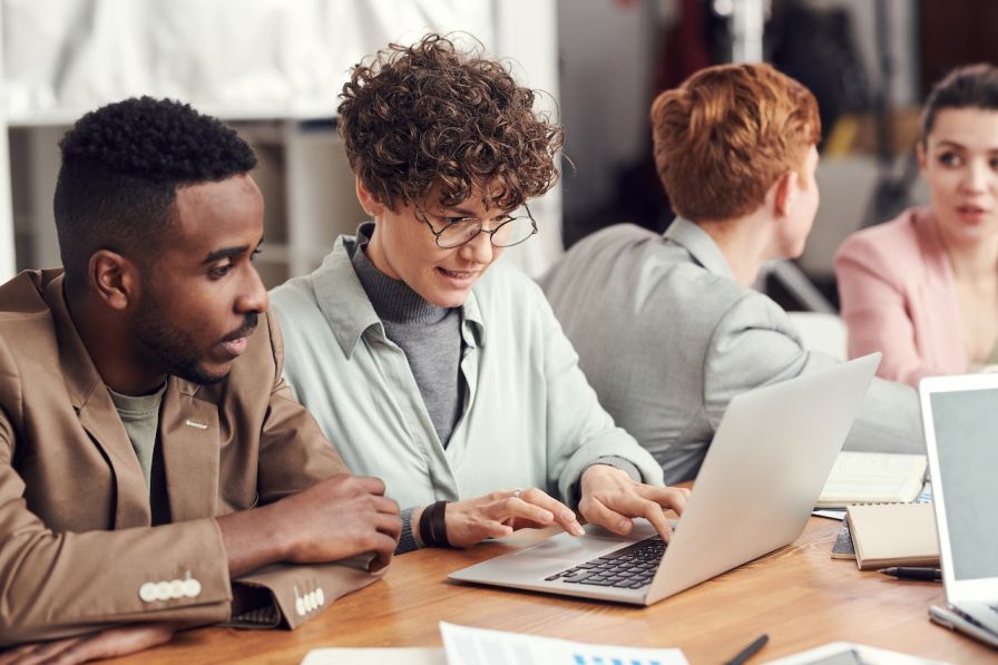 Two people in front of a laptop using Pronouns in Email Signatures