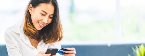 Consumer holds phone and credit card in hand to buy a product from a social media app