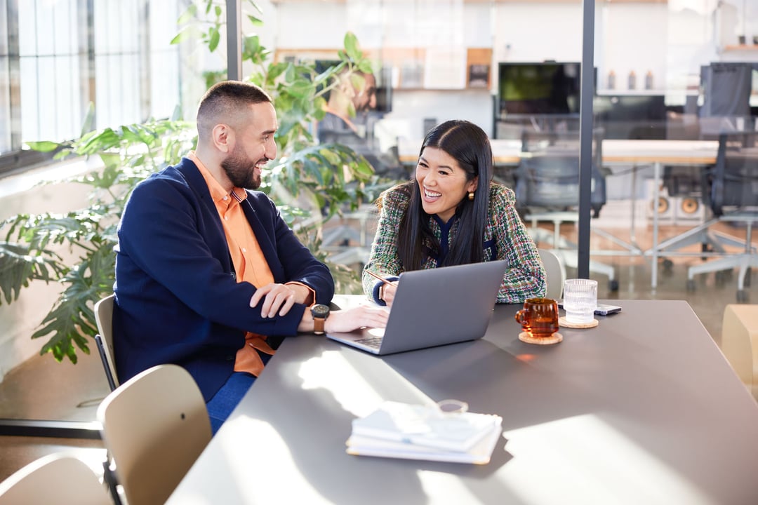 Two professionals smiling in front of laptop