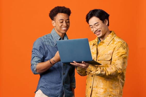Two employees working from a shared laptop screen