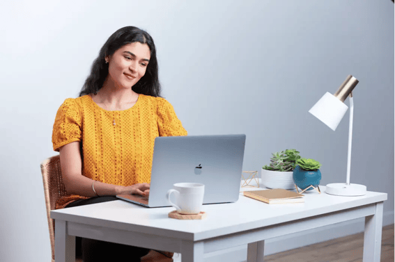 白い机の上でノートパソコンを使って仕事をする女性
