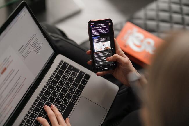 femme regardant son téléphone devant son pc