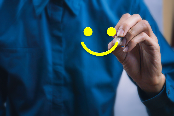 homem desenha um rosto sorrindo em parede com espelho - sucesso do cliente e customer success 
